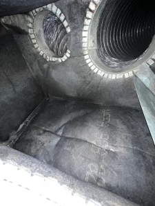 An interior view of the same plenum box after professional cleaning, showing the metal surfaces and duct openings free of debris, mold, and dust, with a noticeably reflective and sanitized appearance